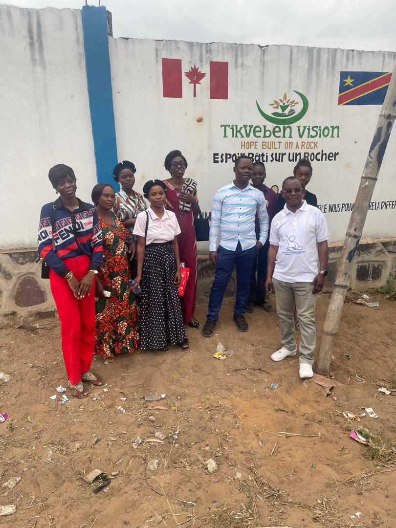Tikveben Vision team in front of the organization's wall in Kinshasa